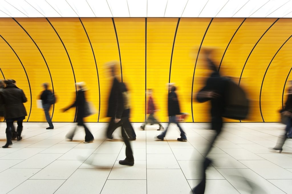 People blurry in motion in yellow tunnel down hallway People blurry in motion in yellow tunnel down hallway