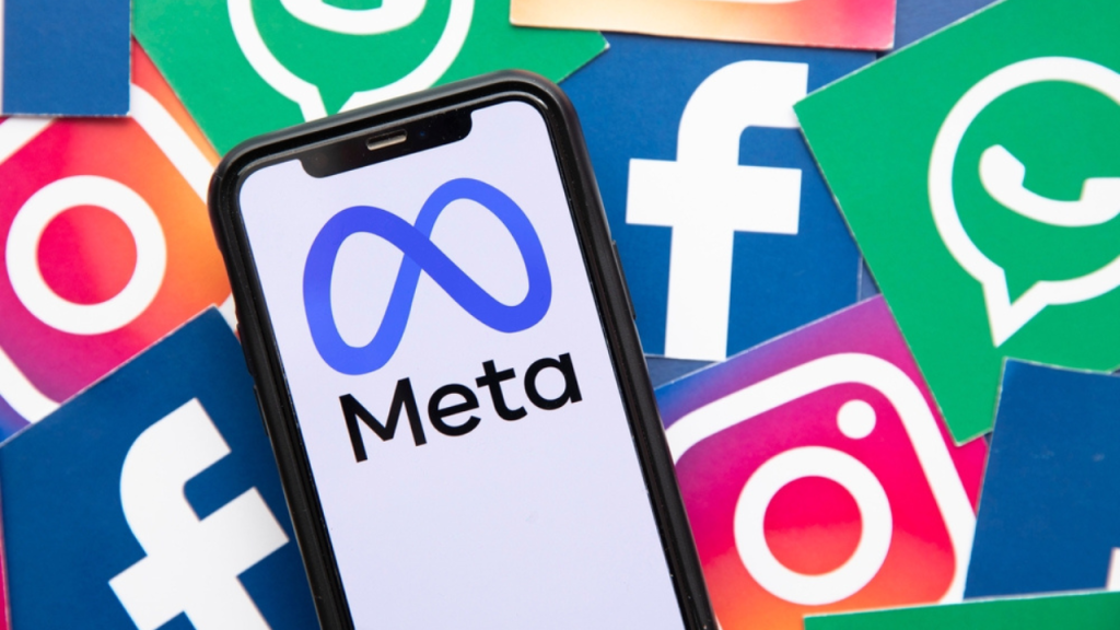 Meta logo on mobile phone with Facebook, Instagram and Whatsapp logos in the background