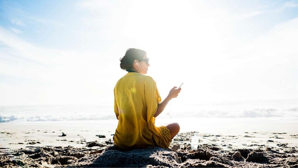 Lady on beach relaxing with mobile phone