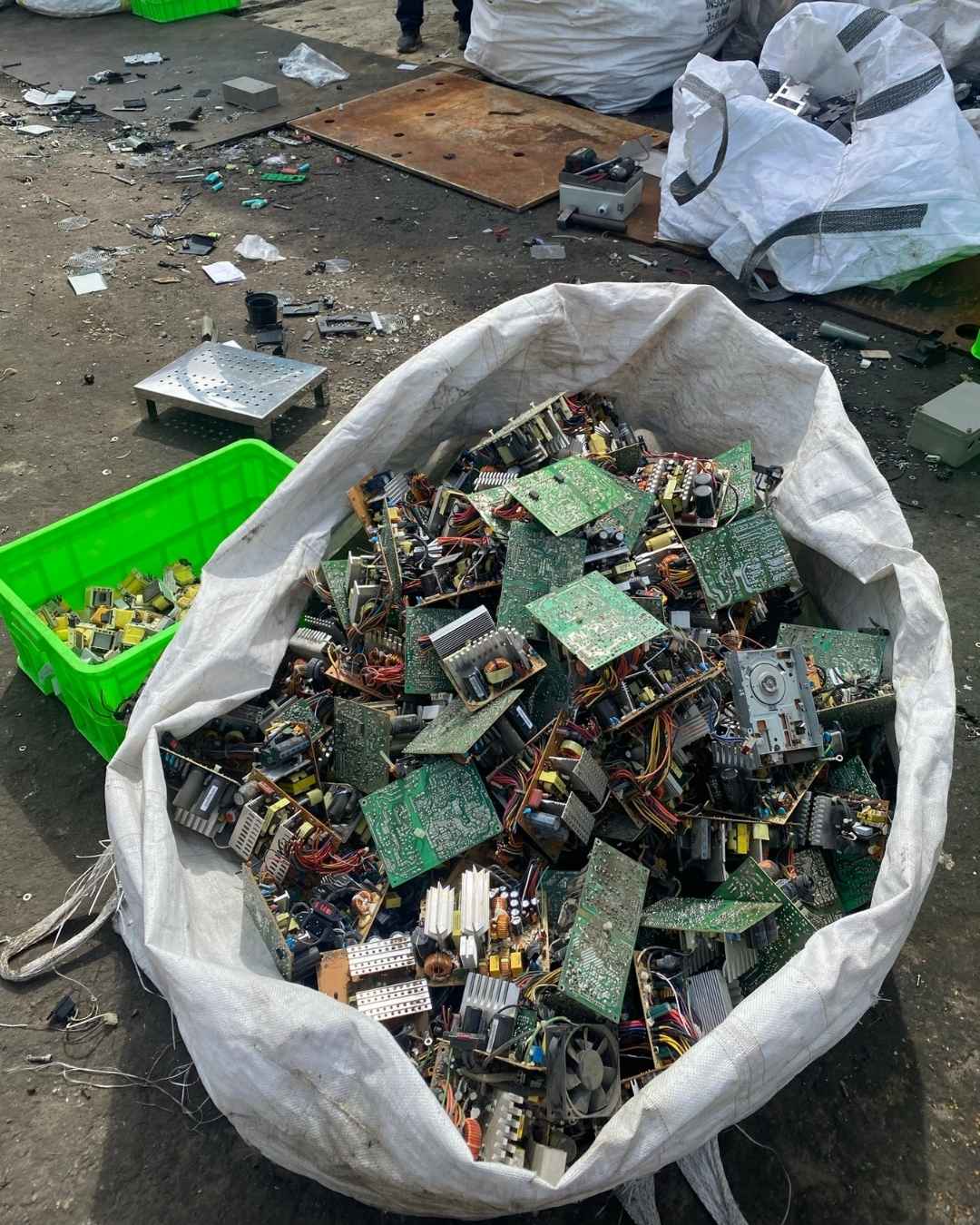 A large beige industrial sack filled with discarded circuit boards and electronic components
