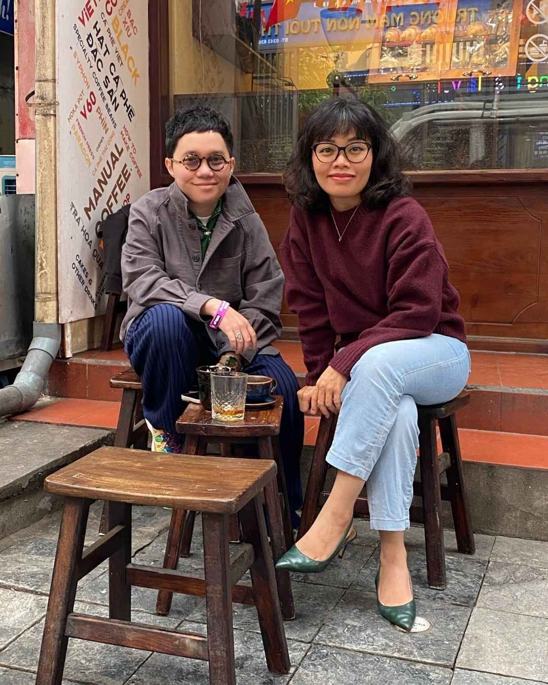 Dang and Phuong sit at an outdoor cafe smiling at the camera