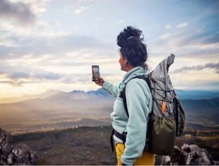 Digital Divide Bushwalking female, looking for phone reception from the top of a mountain in remote Tasmania, Australia.