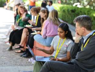 Mark Sanderson with student sitting outside in sun, other researchers in the background