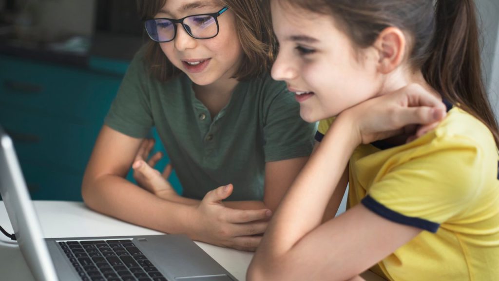 Two kids using a laptop to communicate with an AI assistant.