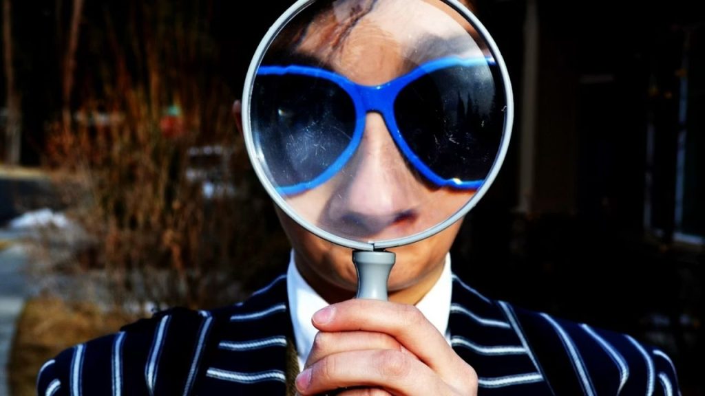 Person holding magnifying glass to their face