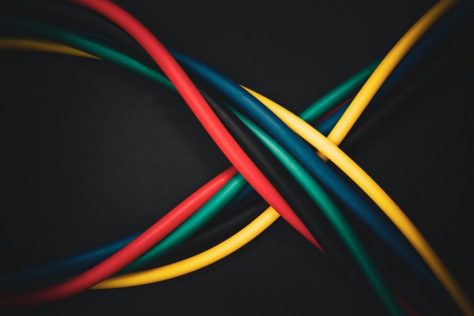 red, green and yellow computer cables twisting ober a black background